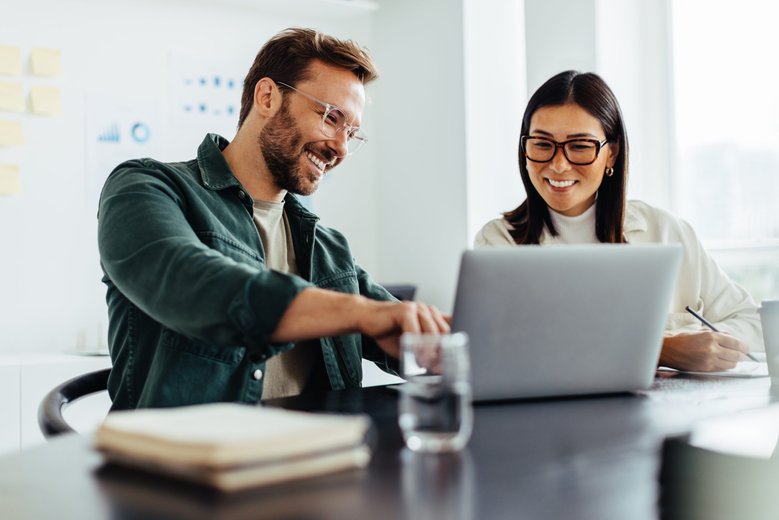 Two professionals collaborating with a laptop in an office